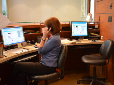 Orthodontic office receptionist scheduling appointments on phone at front desk workstation in Vancouver clinic